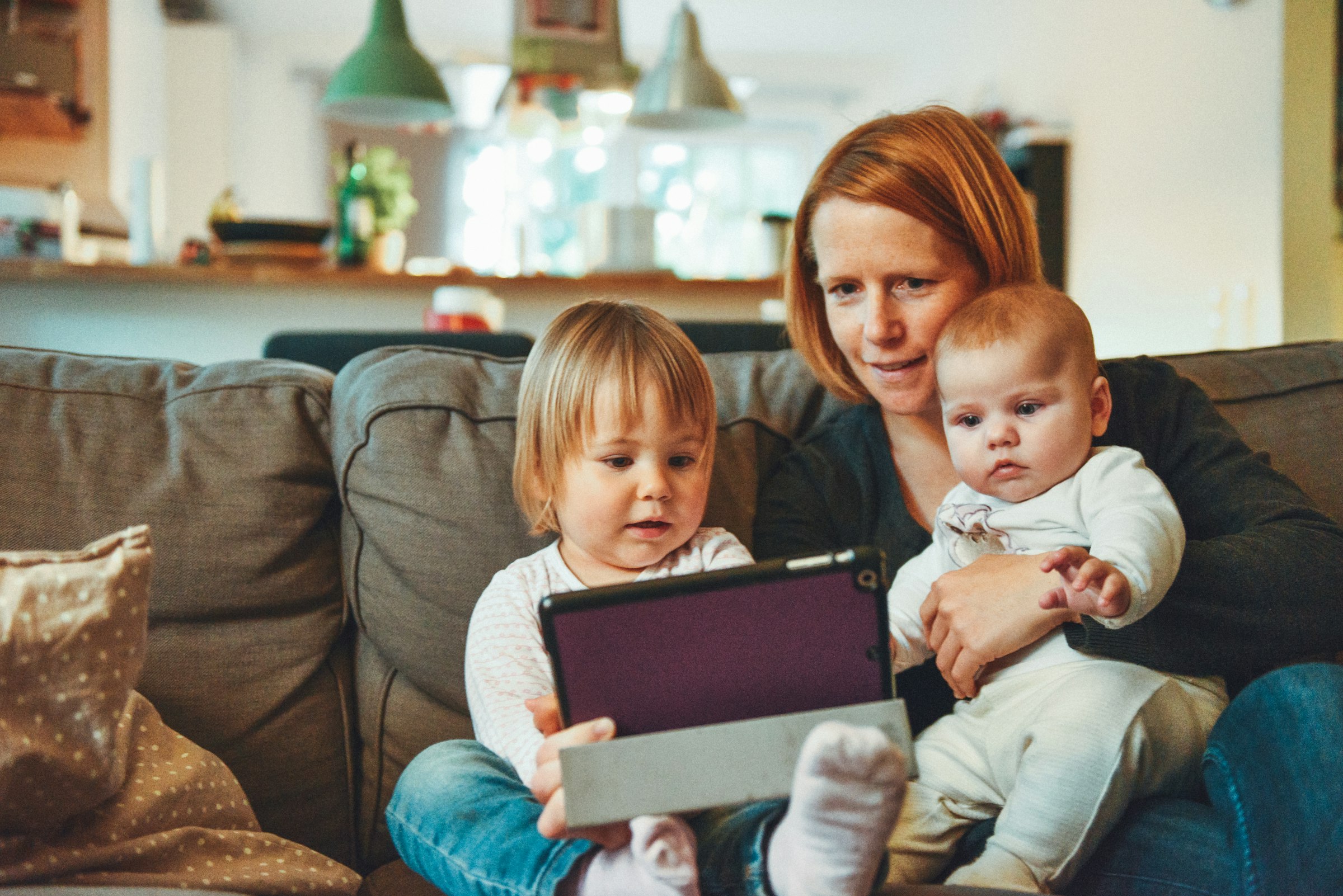 Parent and child laughing while watching content together on a tablet